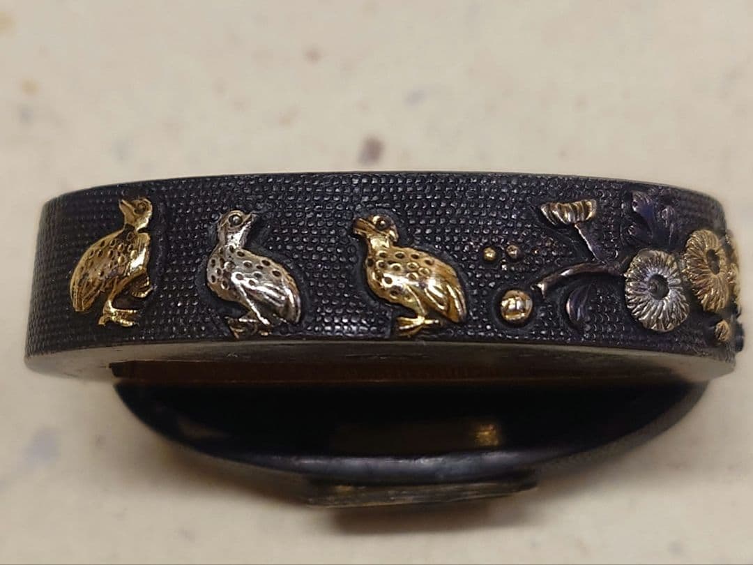 縁頭、赤銅魚子地に秋草に鶉図